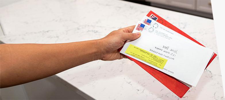 Person holding stack of forwarded USPS mail.